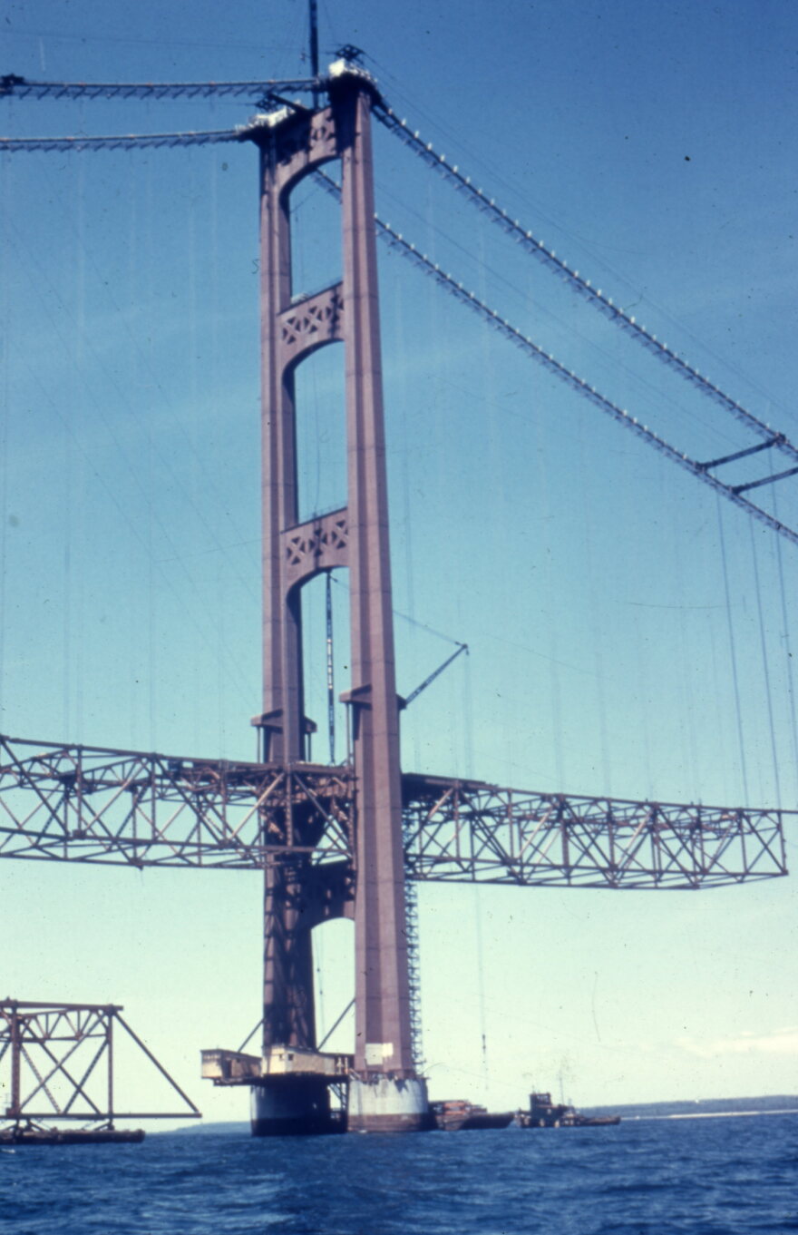The construction image features one of the Mackinac Bridge's tower girders being constructed over the Straights of Mackinac.