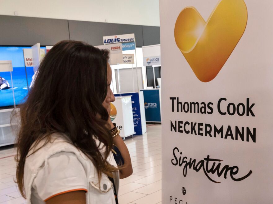 Thomas Cook's collapse has left more than 150,000 travelers scrambling for details about how to get home. Here, a worker at a travel agency that partners with Thomas Cook talks on the phone at Larnaca International Airport in the Cypriot coastal city.