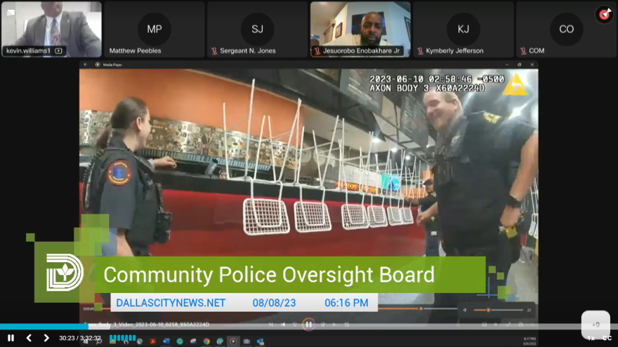 A Zoom video meeting screen shows a horizontal row of screens of meeting attendees, two showing video of individuals sitting behind a camera and three showing black screens with initials and names of meeting attendees. Below is a screenshot of police body camera footage showing two officers standing on opposite sides of the screen, talking, with a third barely visible in the background to the right. Behind them in the footage is a row of white chairs turned upside down on a red countertop. Text overlaying the video reads "Community Police Oversight Board."