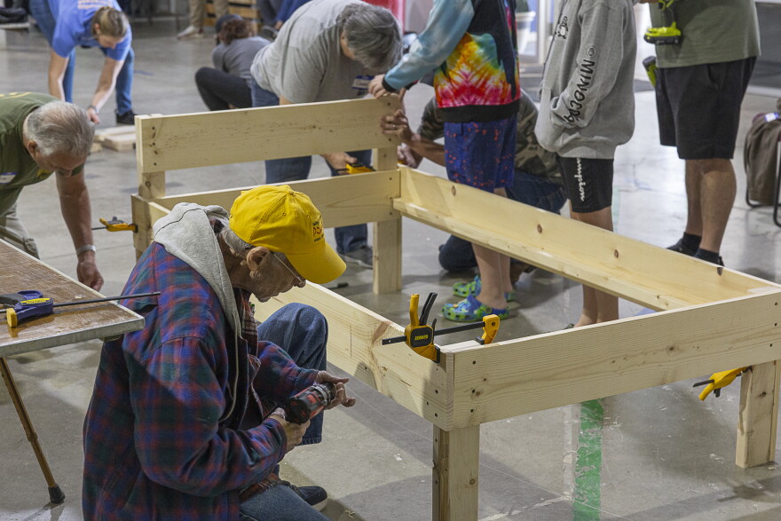 A man is kneeled down building a bed frame.