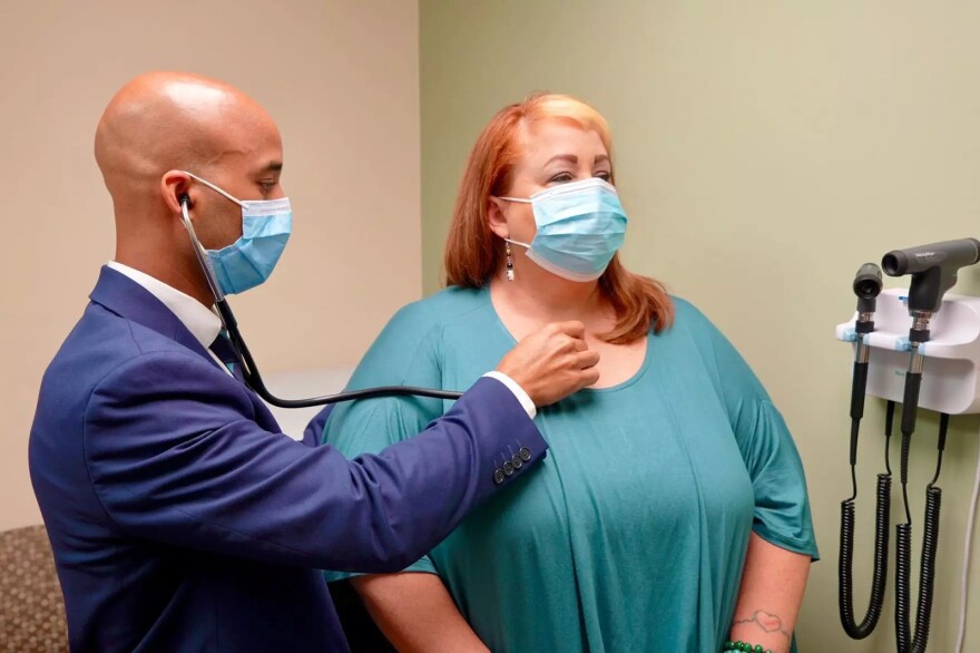Dr. Dwayne Gordon, lead physician of AdventHealth's Post-COVID Clinic in Orlando, checks the breathing of Tanya Balyeat, a long COVID patient from Mount Dora.
