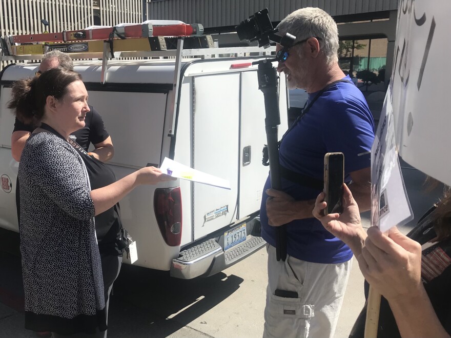 A library staffer presents Drew Ribar (right) with written notice of his temporary suspension on June 20, 2024.