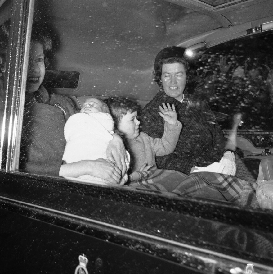 Queen Elizabeth II holds her fourth child, Prince Edward, as they head to Windsor Castle with Prince Andrew in 1964.