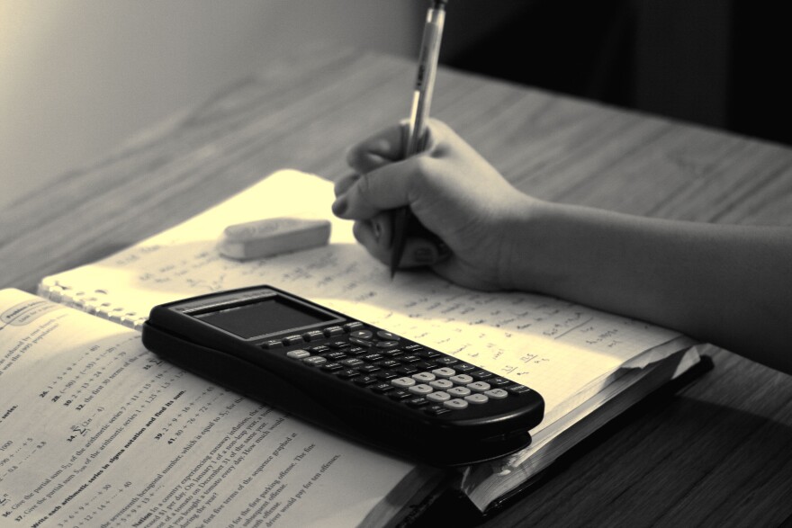 Person studying math with a notebook and a calculator.