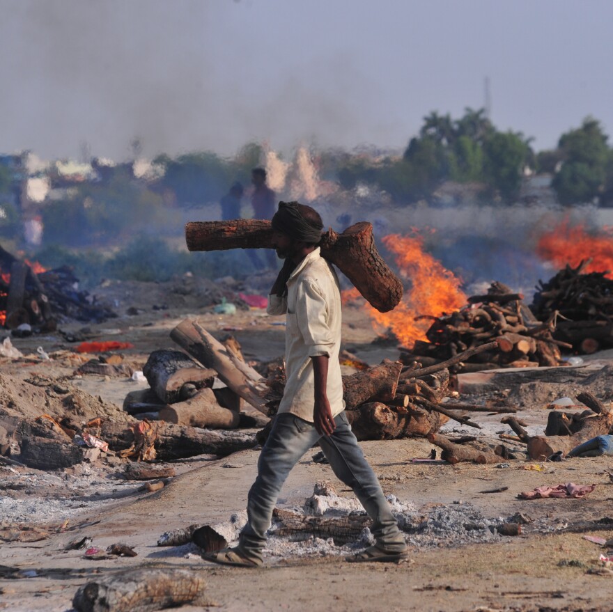 A worker carries wood to a mass cremation site for Indians who died of COVID-19. The photo was taken on the banks of Ganga River in Allahabad on April 27.