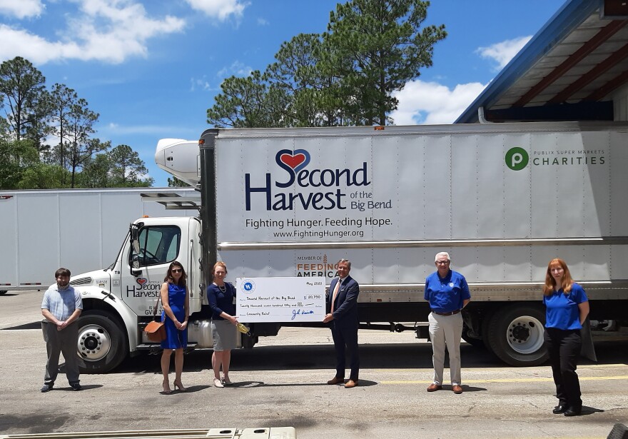 Second Harvest of the Big Bend CEO Monique Ellsworth (holding the ceremonial check on the left) receives the donation from Hancock-Whitney Market President Tom Dieson.