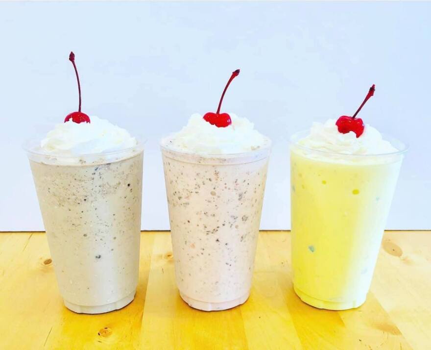 Three different flavors of milkshake, each topped with whipped cream and a cherry.