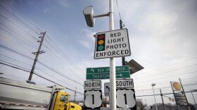 A truck passes a red light photo enforcement sign that is placed below a red light camera at the intersection of Route 1 and Franklin Corner Road Tuesday, Dec.16, 2014, in Lawrence Township, N.J. (AP Photo/Mel Evans)