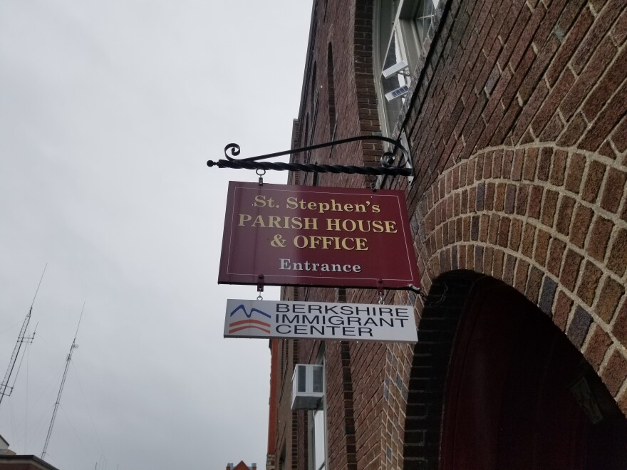 A sign hangs from a brick arch against a grey sky