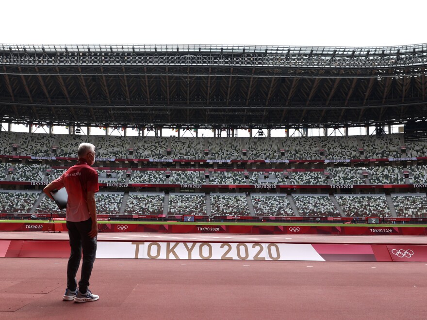 A passerby looks on while wearing a protective face covering inside an empty Olympic Stadium, host to the Athletics competition, at the Tokyo Olympic Games on Thursday.