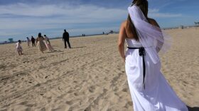 Bride Lorena James walks toward her wedding ceremony before she is married to husband Steven on the beach on Valentine’s Day in Huntington Beach, California.