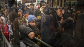 People try to get on a bus as they leave Kyiv, Ukraine, Thursday, Feb. 24, 2022. Russia launched a wide-ranging attack on Ukraine on Thursday, hitting cities and bases with airstrikes or shelling, as civilians piled into trains and cars to flee.