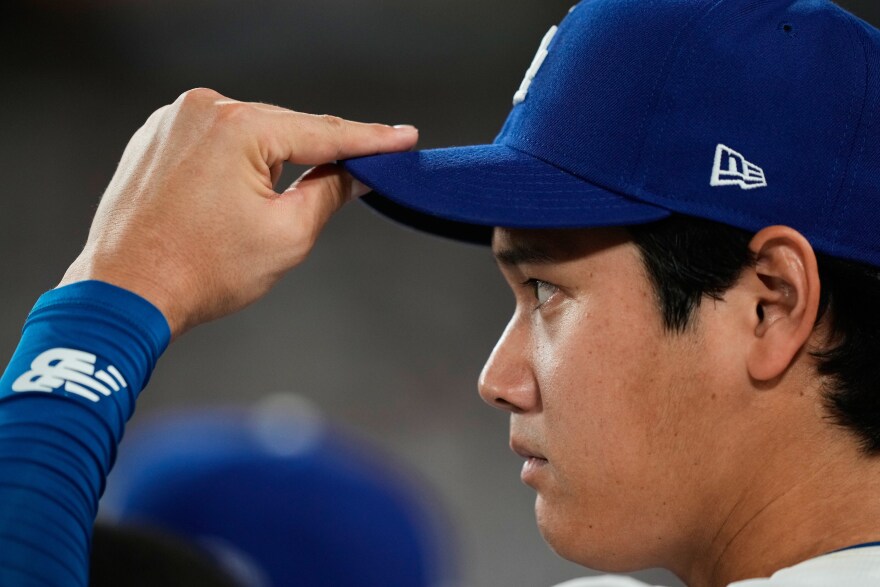 Los Angeles Dodgers' Shohei Ohtani watches from the dugout during the fifth inning in Game 1 of the National League Wild Card baseball playoff series against the Cincinnati Reds, Tuesday, Sept. 30, 2025, in Los Angeles. (AP Photo/Mark J. Terrill)