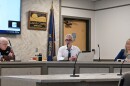 Three people sitting at a dais during a public meeting. 