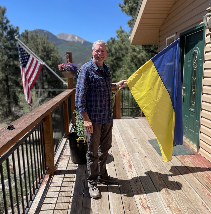 Physicians assistant Bob Downs holding a Ukrainian flag in front of his home in Lake City, Colorado.