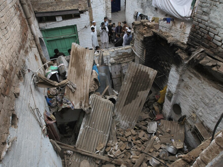 People stand outside a house damaged from an earthquake in Peshawar, Pakistan, after a powerful earthquake in northern Afghanistan rocked cities across South Asia.