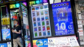 An electronic sign hanging at a convenience store announces a Powerball jackpot exceeding 1 billion dollars as a man leaves the store with his lottery tickets, Wednesday, July 19, 2023, in New York. The new jackpot for Wednesday’s Powerball drawing would be the seventh highest in U.S. history and the third largest for the game. (AP Photo/Mary Altaffer)