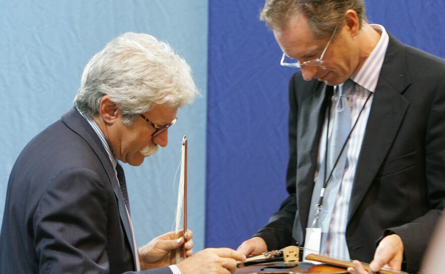 Appraisers Fred Oster (left) and David Bonsey, review a 1920 French violin at an <em>Antiques Roadshow</em> event in Los Angeles in 2005. Many stringed instruments throughout history have been made using small amounts of ivory.