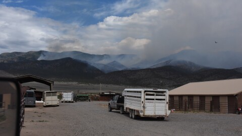 In an undated photo provided by Emma Wilde, smoke rises from the Cottonwood Fire near a field with trucks and cattle trailers ready to evacuate.