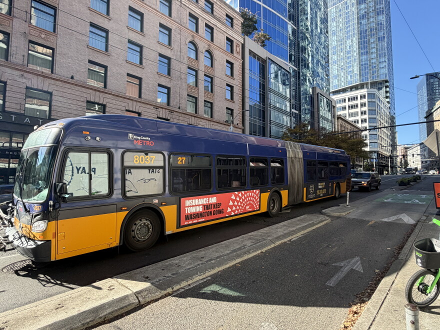 A photo of a yellow and purple King County Metro bus in downtown Seattle. 
