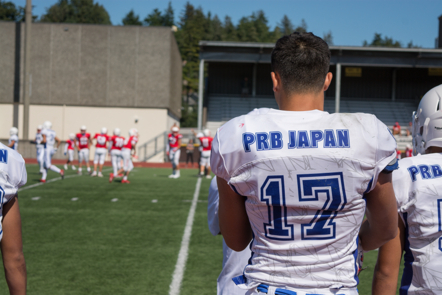 A Japanese player stands at the sidelines of the football game.