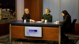 Three people sit at a desk while a screen displays a logo that says "Alaska Insight"
