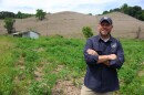 Jacob Stewart, Private Lands Program coordinator for Kentucky Fish and Wildlife Resources, poses before a hillside in Whitley County covered in dying kudzu. Around him, native plants and fauna choked out by the vine have already sprouted in its place. The 26-acre property once housed a coal mining operation and was one of eight sites statewide where the new treatment was studied.