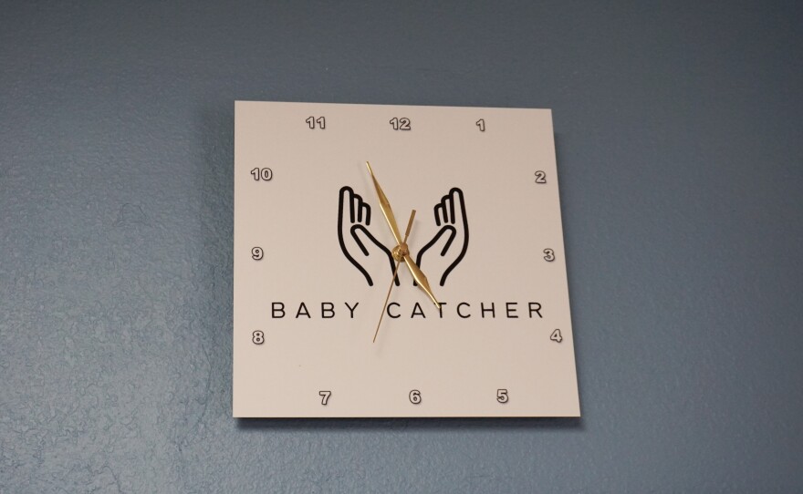 A clock hanging in the Mountain Heart Midwifery waiting area says "baby catcher," one way to refer to midwives.