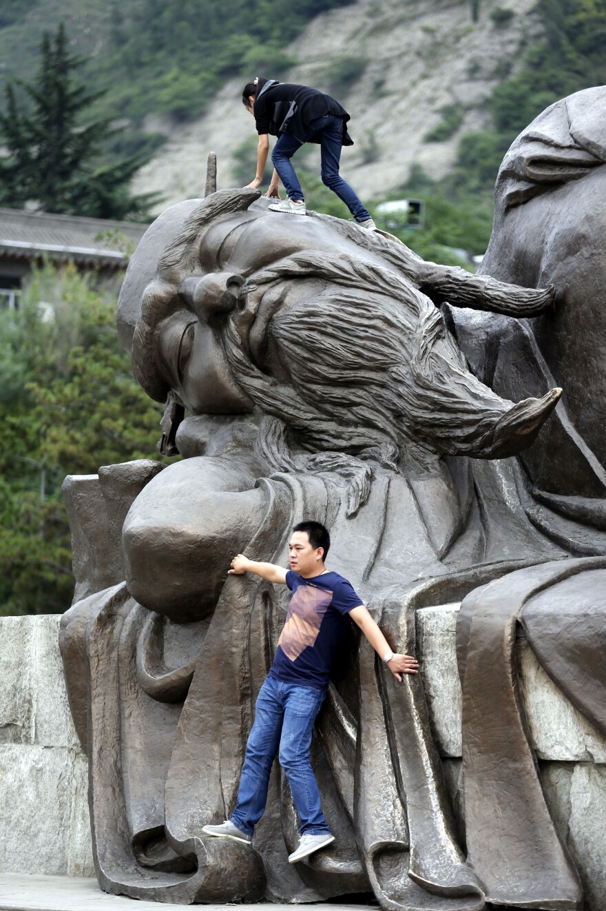 Not exactly what that's for: Two tourists climb on a statue in Huayin, China, near <a href="http://www.npr.org/blogs/thesalt/2015/04/21/401253598/tea-tao-and-tourists-china-s-mt-hua-is-three-part-harmony">Huashan,</a> or Mount Hua, a famed tourist destination, in May 2013.