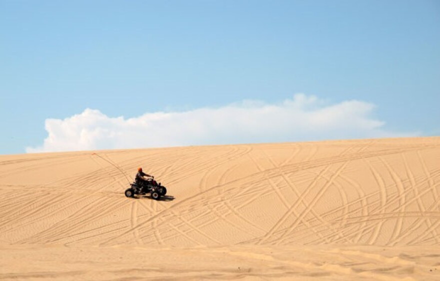 A man rides an ATV across the sand at Beaver Dunes, a former state park recently acquired by the City of Beaver.