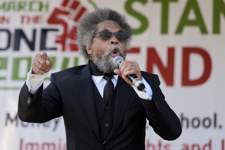 A man speaks into a microphone while wearing a suit.