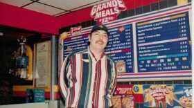 Charles McKenry poses in front of the menu at Juneau’s downtown Taco Bell in 1999. (Photo courtesy of Charles McKenry)