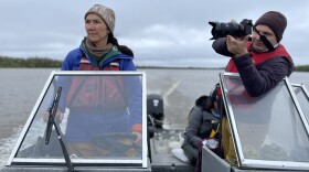 woman drives boat while passenger uses his camera