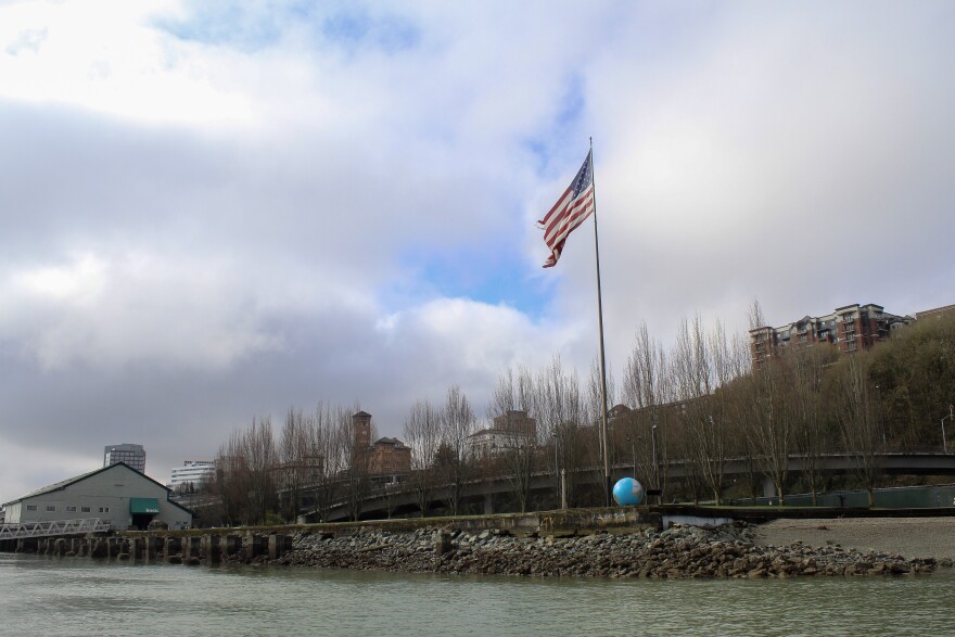 A small waterfront park is pictured featuring a blue globe and American flag flying above it