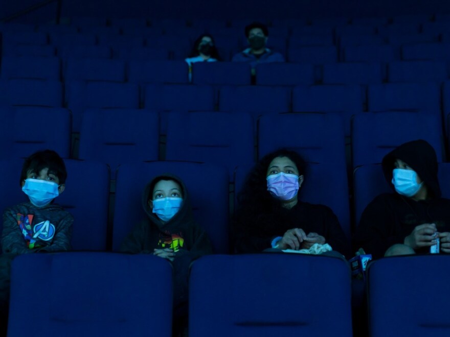 Visitors wear face masks while watching a presentation in a theater at the Aquarium of the Pacific on its first day of reopening to public in Long Beach, Calif., Tuesday, March 16, 2021.