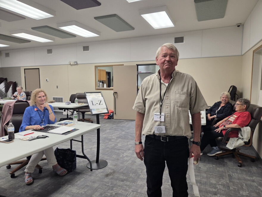 Bagley election judge Mark Edevold stops to smile for a photo with a roll of "I Voted" stickers in his hand