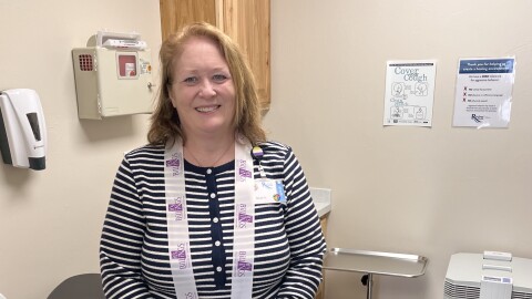 Giblert with RiverStone Health stands in front in one of the new clinic exams rooms at Montana Rescue Mission.
