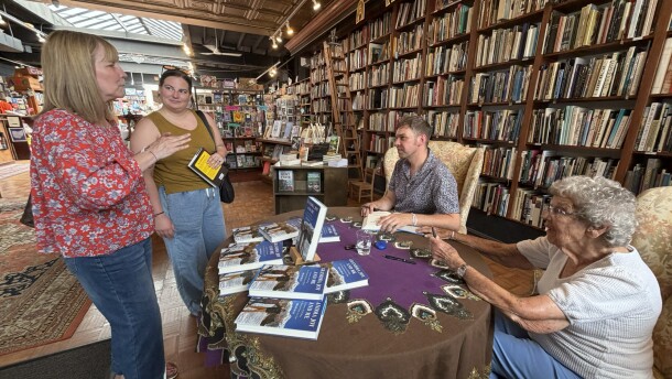Brad Ryan and his grandmother Joy Ryan sign copies of his book while sitting at a table for fans during an book store signing. 
