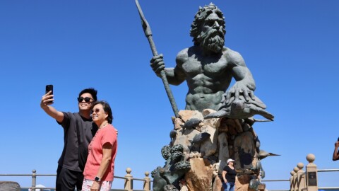 Patrick Vith of Portsmouth takes a picture with his mother, Pim Vith, visiting from the West Coast, with the King Neptune statue behind them on Friday, Aug. 29, 2025.