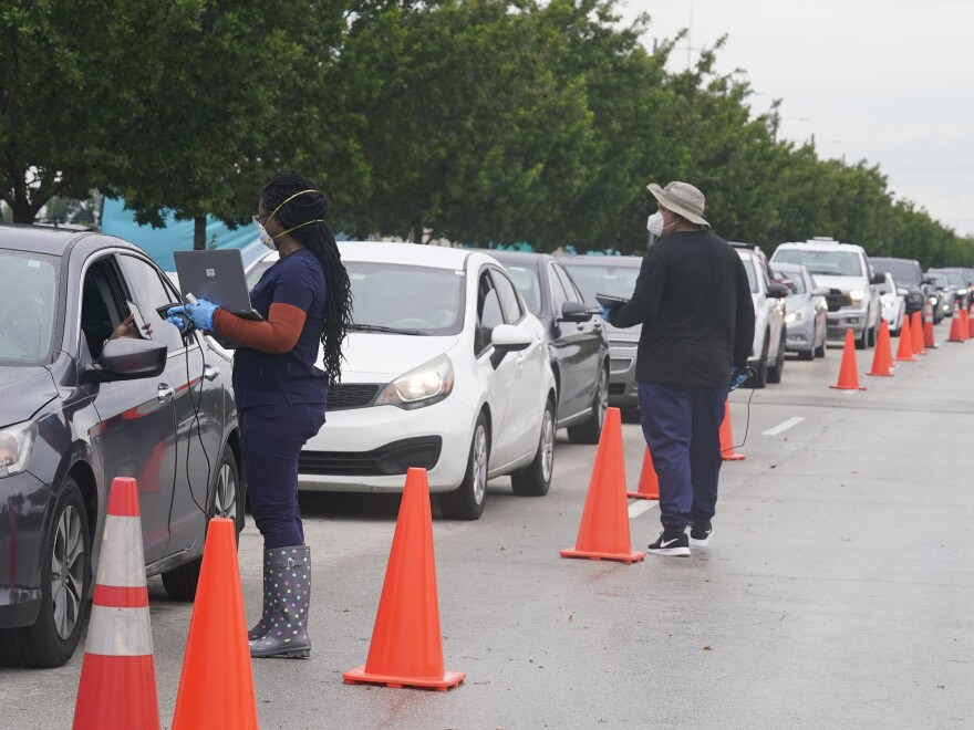 Employees of Nomi Health check in a long line for COVID-19 tests Tuesday in North Miami, Fla. The omicron variant has unleashed a fresh round of fear and uncertainty for travelers, shoppers and party-goers across the U.S.