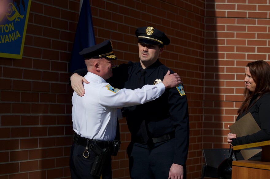 Scranton Police Chief Thomas Carroll, left, hugs Det. Kyle Gilmartin during a welcome home ceremony for the wounded officer at SPD Headquarters on Friday. With Gilmartin is his wife Lindsay.