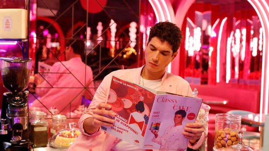 Man holds a magazine in bright pink room