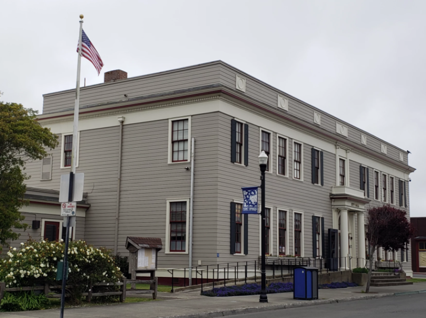 A two-story gray building with narrow windows on a street corner.