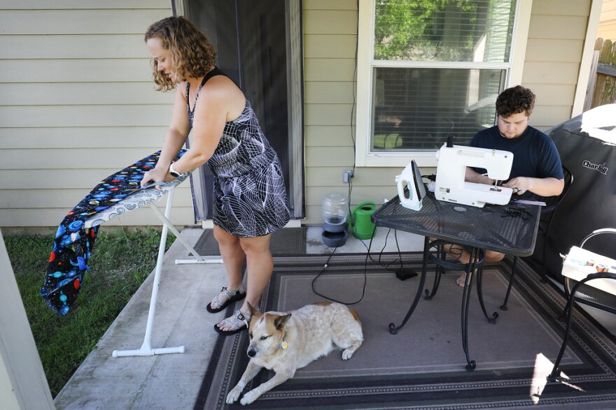 Joni Watkins and Matt Umberger sew face masks to donate to health care workers, on the porch of their South Austin home.