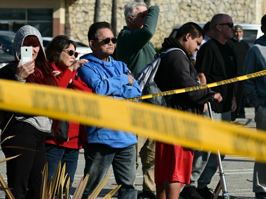 Bystanders watch law enforcement agents breaking into the van where the suspect in the Monterey Park shooting took his own life on Sunday.