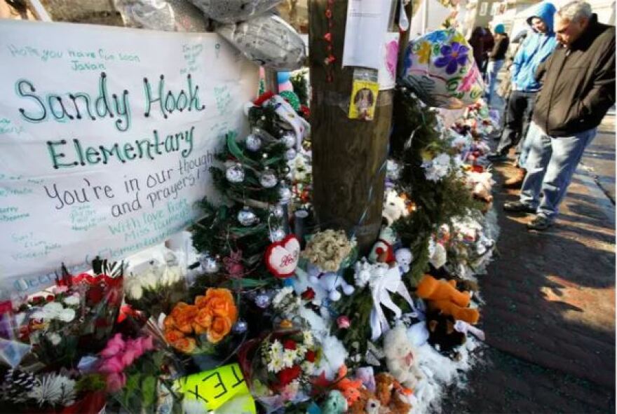 People stop to look at a makeshift memorial at Sandy Hook Elementary School in Newtown, Connecticut, two weeks after a gunman shot and killed 20 students and six adults in the school on Dec. 14, 2012.