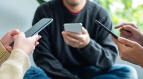 Group of young people using and looking at mobile phone together