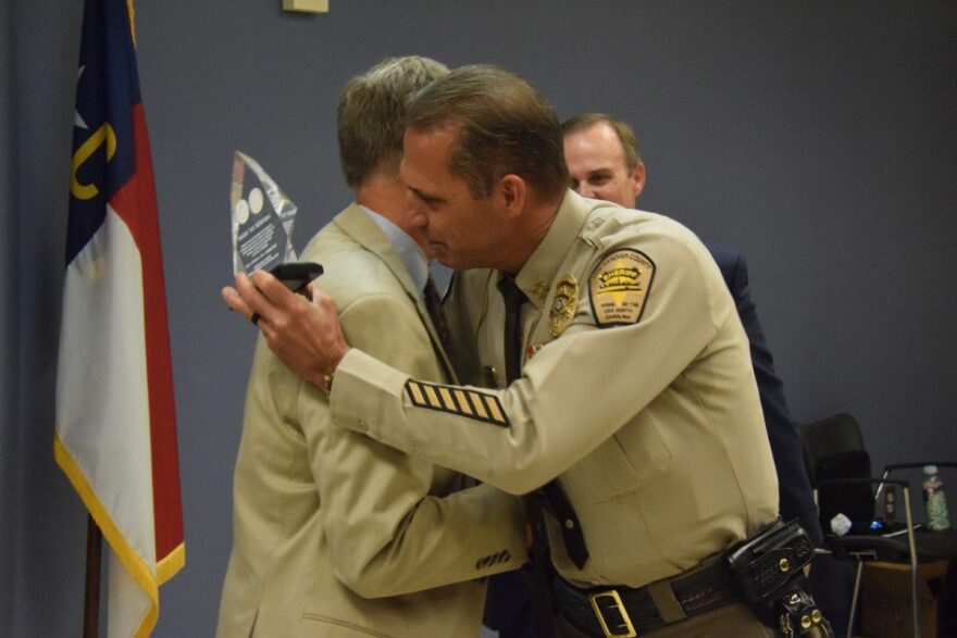 Sheriff Ed McMahon giving an award to former deputy superintendent Dr. Rick Holliday, recognizing their long-standing partnership.