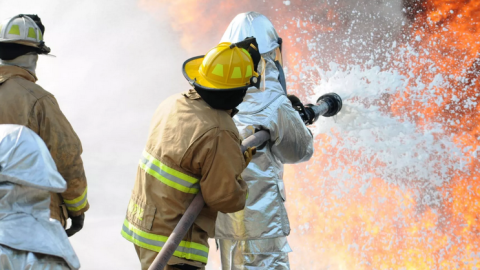 Firefighters blast a stream of aqueous film-forming firefighting foam in a training event. The foam contains PFAS, a substance that causes serious human health problems.