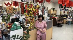 A small Vietnamese woman poses at the register in a hair salon decorated with red decorations and yellow flowers in honor of the Lunar New Year